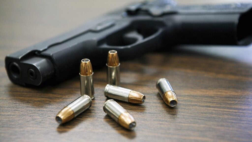 Handgun with bullets on a wooden table